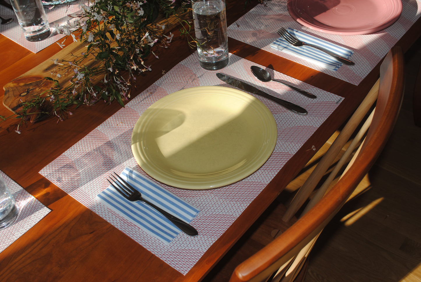 Seersucker Stripes paper napkins. Blue and white striped napkins linen feel airlaid napkins. Image of striped dinner napkins folded with silverware and pink placemats as part of a dinner table setting.